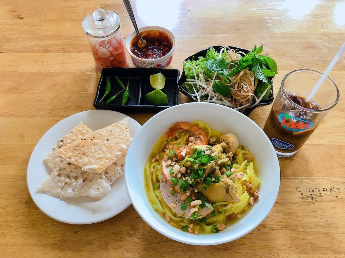 Golden Mi Quang noodles served with fresh herbs and crisp rice crackers at Mi Quang 92